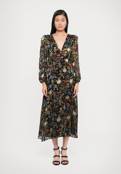 Robes noires à imprimé floral avec de longues manches bouffantes et un décolleté en V profond ; tissu léger, longueur jusqu'à la cheville, associée à des sandales noires à brides.
