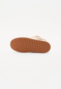 Sneaker sole with a textured rubber design in tan, featuring a geometric pattern for grip and a smooth edge. No visible logos or accents.