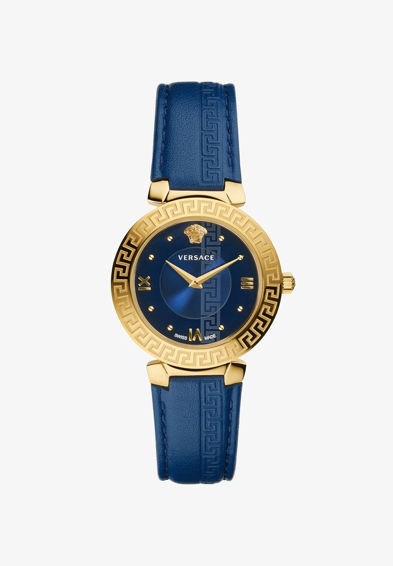 Guldtonad klocka med blå urtavla, blå läderrem med mönster och grekisk nyckelmönster på bezeln. Romerska siffermarkörer för timmar.