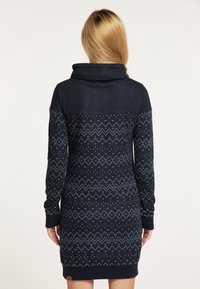 Meripuku, jossa on kauluksen muotoinen pääntie ja pitkät hihat. Siinä on kevyen sininen geometrinen kuvio, ribbaus hihansuissa ja helman yksityiskohta lähellä alareunaa.