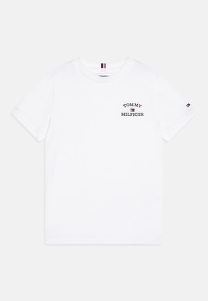 Hvid T-shirt med korte ærmer og rund hals med lille "Tommy Hilfiger" tekst og flaglogo på brystet samt flaglogo på venstre ærme.