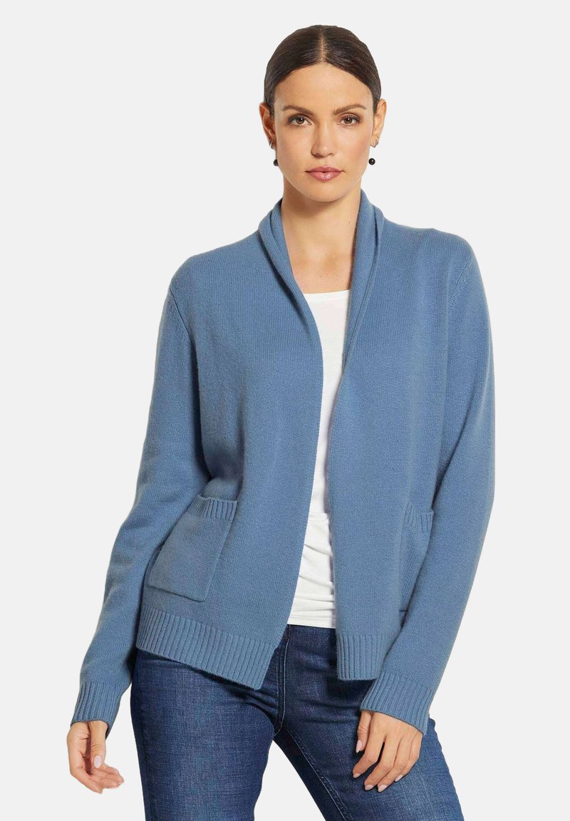 Hellblauer Cardigan aus weichem Strickmaterial, mit Schalkragen, zwei Fronttaschen sowie gerippten Bündchen und Saum.