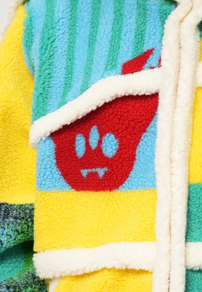 Fleece jacket featuring colorful sections: bright yellow, blue, green, and red. Notable red monster graphic with blue accents; soft texture.