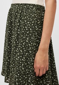 Grüner, mit Blumenmuster versehener Rock aus leichtem Material, mit elastischem Bund und fließender Silhouette, verziert mit kleinen weißen Blumen.