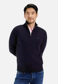 Pull-over marine avec col zippé et côtelé aux poignets et à l'ourlet. Mélange de coton avec une texture lisse et petit logo en détail sur la poitrine.