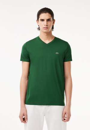 Grünes V-Ausschnitt-T-Shirt aus weicher Baumwolle. Verfügt über kurze Ärmel, einen slim fit und ein kleines gesticktes Logo auf der linken Brust.