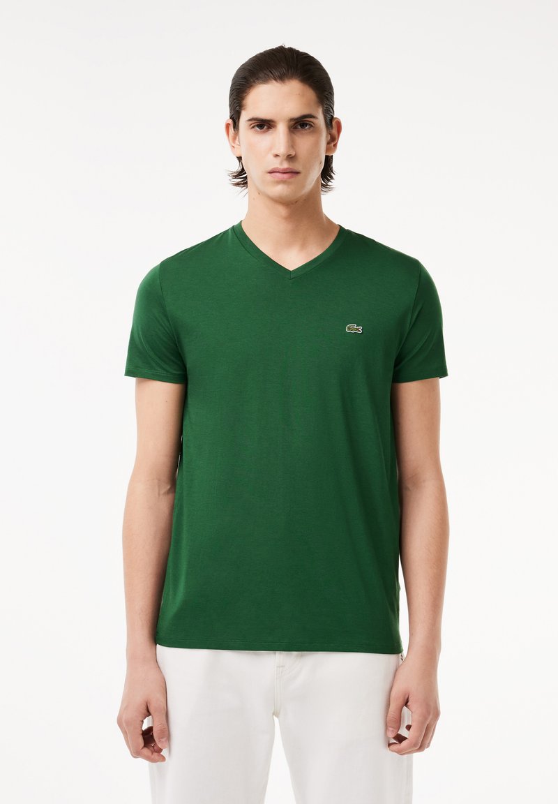 T-shirt verde a scollo a V realizzato in morbido cotone. Presenta maniche corte, una vestibilità slim e un piccolo logo ricamato sul lato sinistro del petto.
