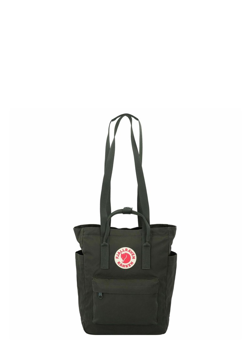Bolso tote de color verde oscuro hecho de tela resistente. Tiene dos correas largas, un bolsillo frontal, una etiqueta con el logotipo y bolsillos laterales para almacenamiento adicional.