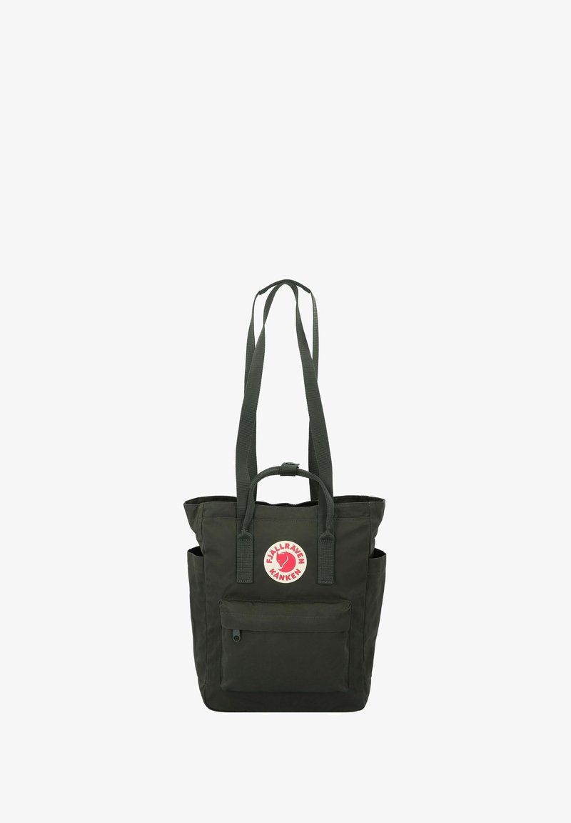 Bolso tote de color verde oscuro hecho de tela resistente. Tiene dos correas largas, un bolsillo frontal, una etiqueta con el logotipo y bolsillos laterales para almacenamiento adicional.