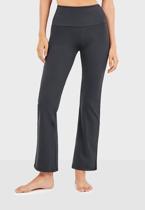 Pantalones de yoga negros de campana hechos de una tela elástica con una cinturilla alta. Textura suave y diseño ajustado desde la cintura hasta la rodilla, con un corte acampanado en la parte inferior.
