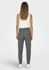 Szare spodnie dresowe z elastycznym paskiem w talii, kieszeniami bocznymi i tylnymi oraz zwężającą się nogawką, zestawione z białymi sneakersami.