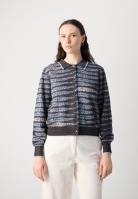 Strikket cardigan med en mørk bund, prydet med lys blå og grå bladmønstre, en krave-udskæring og knaplukning foran. Strukturerede ærmer og kant.
