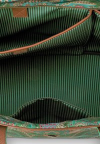 Open groene handtas met bloemmotief, die een binnenvoering van groen en zwart verticale gestreepte stof toont, met rits- en open zakken.
