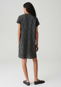 Abito a maniche corte, lunghezza al ginocchio, di colore blu navy con un motivo astratto verde. Realizzato in tessuto leggero, presenta una vestibilità comoda e un orlo arrotondato.