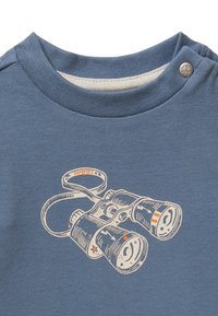 Blauwe katoenen t-shirt met een grafiek van verrekijkers in witte en oranje accenten. Drukknoop op de schouder voor gemakkelijke bediening.