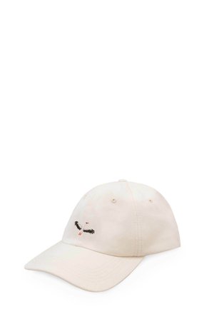 Beżowa czapka z daszkiem z haftowanym czarno-białym ptakiem z pomarańczowymi stopami i dziobem na przednim panelu.