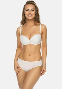 Weißer Spitzen-BH mit gepolsterten Cups, zarten gewellten Rändern und verstellbaren Trägern, kombiniert mit weißen semi-transparenten hochgeschnittenen Slips.