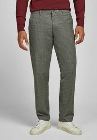 Grijze geblokte broek van een gestructureerde stof, met een knoopsluiting en zijzakken, gecombineerd met witte sneakers.