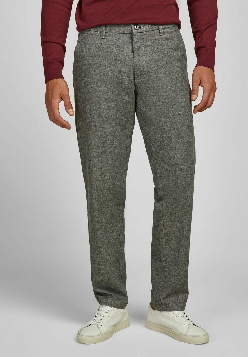 Grijze geblokte broek van een gestructureerde stof, met een knoopsluiting en zijzakken, gecombineerd met witte sneakers.