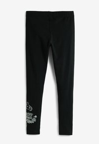 Fekete leggings, puha anyagból, rugalmas derékpánttal. Az egyik bokánál egy karakter és szöveg fehér nyomtatása található.