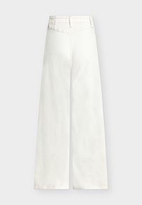 Bijele široke hlače visokog struka s petljama za remen i vidljivim šavom na stražnjoj strani, na jednostavnoj svijetloj pozadini.