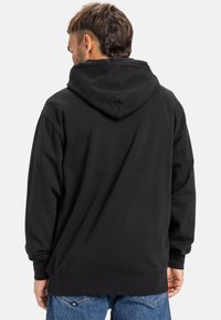 Black hooded sweatshirt with a relaxed fit. Features a kangaroo pocket, ribbed cuffs, and hem. Soft fabric with a smooth texture.