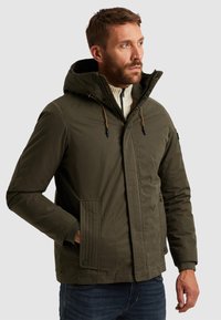 Olivově zelená zateplená bunda s kapucí, zapínáním na zip, elastickými manžetami a dvěma předními kapsami. Strukturální panely podél zipů.