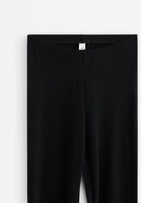 Svarta leggings i stretchigt material, med en slät textur och en sömlös midja med en liten logotag högst uppe.