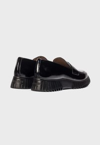 Zwarte gepatineerde leren instap schoenen met een gestructureerde ribbelzool en een ronde voorkant. Gladde afwerking en minimalistisch ontwerp zonder veters.