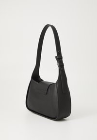 Borsa a spalla in pelle nera con forma curva, tasca frontale piatta, tracolla regolabile e superficie liscia. Minimalismo negli accessori metallici.