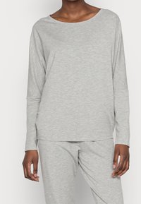 Camiseta de manga larga gris claro con escote barco y ajuste relajado. Fabricada en una suave tela texturizada con hombros anchos y caídos.