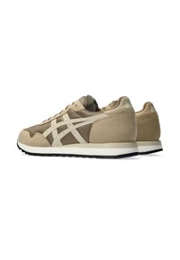 Tan athletic sneakers with a smooth suede and mesh upper, featuring cream accents and a black rubber sole. Low-profile design with laces.
