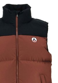 Veste sans manches matelassée avec col montant, corps marron, partie supérieure noire, fermeture éclair frontale, et petit logo circulaire sur la poitrine.
