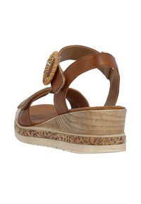Sandale compensée en cuir marron avec accent circulaire tissé, brides réglables et plateforme texturée ornée d'un motif floral.