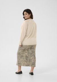 Beige knit sweater paired with a leopard print mid-length skirt. The skirt features a textured fabric with black accents. Black flats.