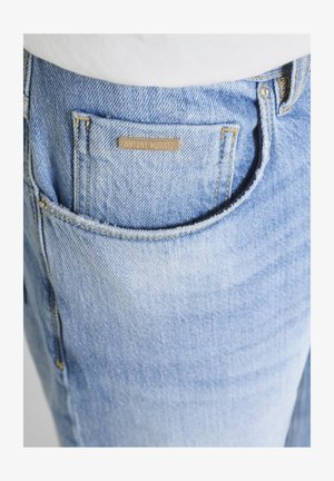 Tasca di jeans in denim azzurro chiaro con una piccola etichetta metallica rettangolare con la scritta "ANTONY MORATO" cucita sopra la tasca.