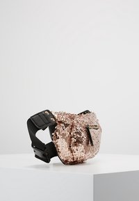 Fanny pack in mini misura color oro rosa con paillettes, dotato di una tracolla nera regolabile e una tasca con zip, esposto su un piedistallo bianco contro uno sfondo semplice.