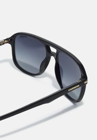 Ochelari de soare din plastic negru, cu lentile gri degradé, având o formă rectangulară elegantă și brandul „CARRERA” în aur pe braț.