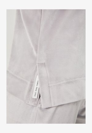 Sudadera de felpa suave en gris claro con un ajuste relajado. Presenta una etiqueta lateral que dice "Cool Cosy Comfy". Detalles de costura visibles a lo largo de los bordes.