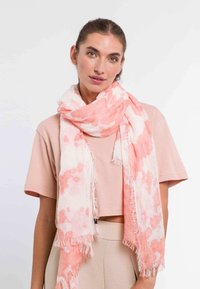 Fular ușor cu un model acquerel în nuanțe de roz și alb, cu margini desfăcute și textură transparentă, aruncat casual.