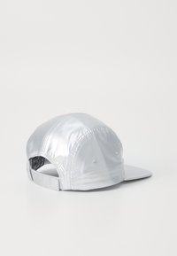 Cappello argentato con finitura lucida, design strutturato e visiera piatta. Cinturino regolabile sul retro, fori di ventilazione e dettagli cuciti.