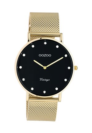 Montre à bracelet en maille dorée avec cadran noir, index en cristal, aiguilles dorées, texte « OOZOO » et « Vintage » sur le cadran.