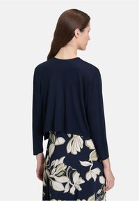 Navy cropped sweater met lange mouwen en een ronde hals, gemaakt van een zachte stof; gecombineerd met een rok met bloemenpatroon in navy en room.