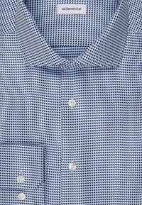 Camicia button-up a righe blu e bianche con colletto aperto, bottoni bianchi e etichetta "seidensticker" all'interno del colletto.