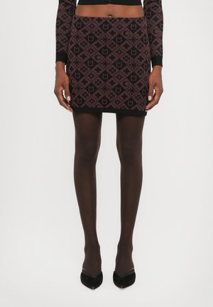 Black mini skirt with maroon geometric pattern, featuring various shapes. Worn with black sheer tights and pointy black heels.