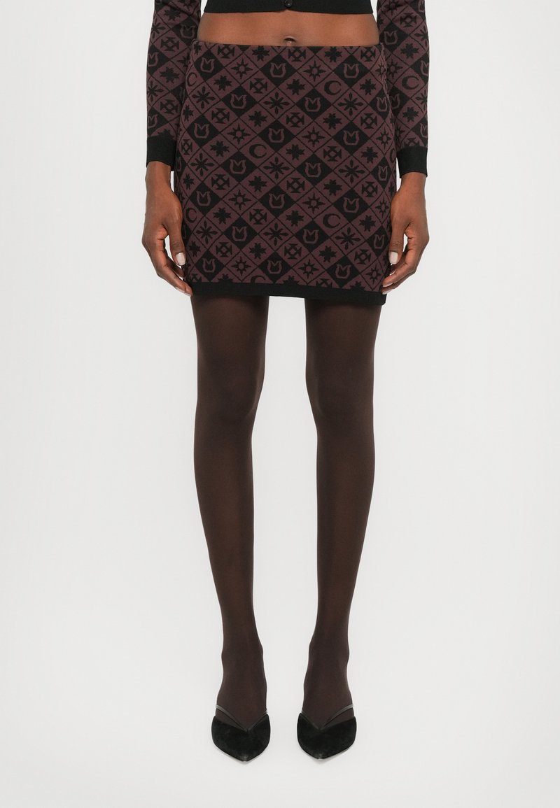 Black mini skirt with maroon geometric pattern, featuring various shapes. Worn with black sheer tights and pointy black heels.