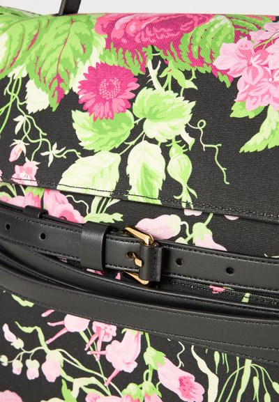 Τσάντα υφασμάτινη με λουλουδάτο σχέδιο, που διαθέτει μαύρες λεπτομέρειες, χρυσή αγκράφα και υφή υλικού. Περιλαμβάνει ροζ και πράσινα φυτικά σχέδια σε σκούρο φόντο.