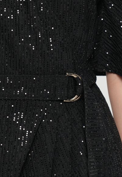 Black textured dress with shimmering sequins, featuring a wide belt with a gold-toned circular buckle and pleated detail at the waist.