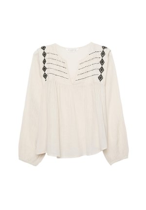 Blouse beige clair avec manches longues, col en V et détails brodés noirs. Présente des plis aux épaules et une coupe ample et fluide.
