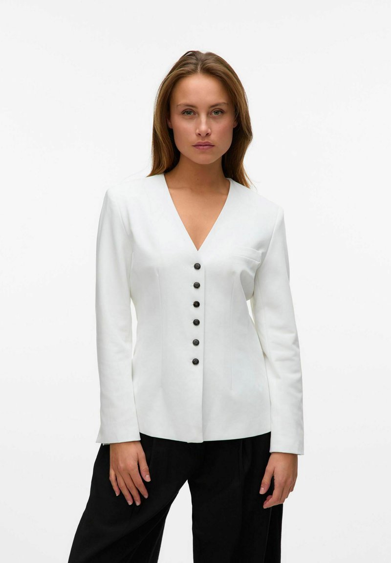 Blazer blanco ajustado con escote en V, mangas largas y seis botones negros en la parte delantera. Textura suave y diseño estructurado.